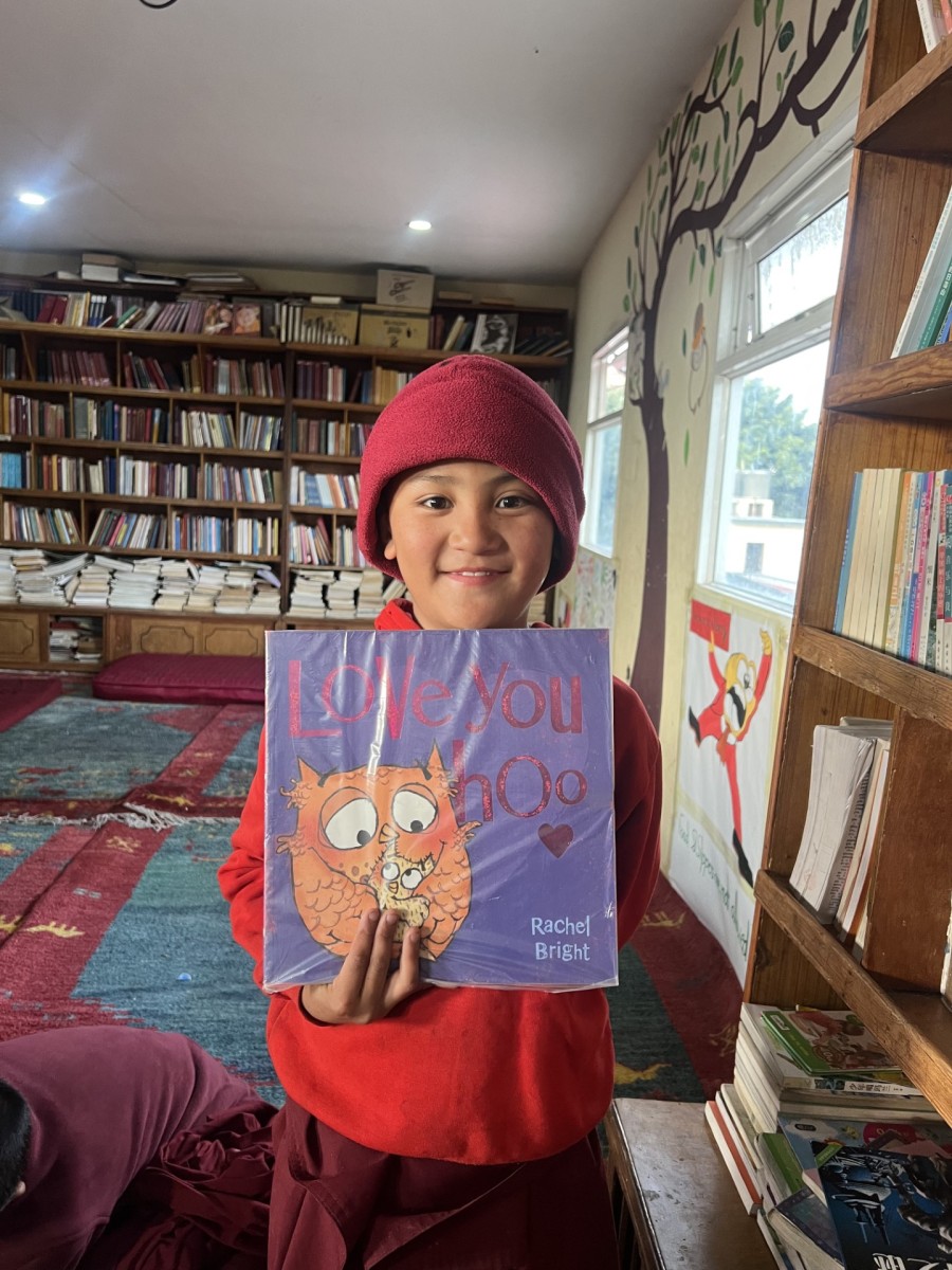 giovane monaco che felice mostra un bel libro nella biblioteca della Sakya Tharig Monastic School a Boudhanath